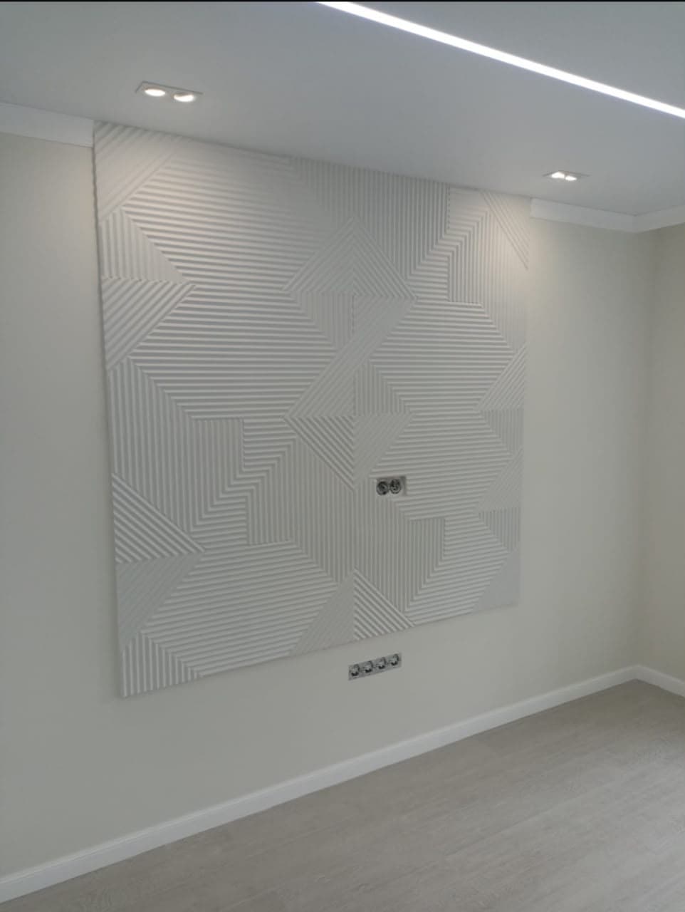 White 3D geometric wall panel with multi-directional ribbed patterns in a modern, minimalist room.